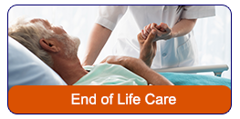 End of Life Care: A health care professional standing behind an elderly man in a wheelchair. She is leaning over and giving the man a hug.
